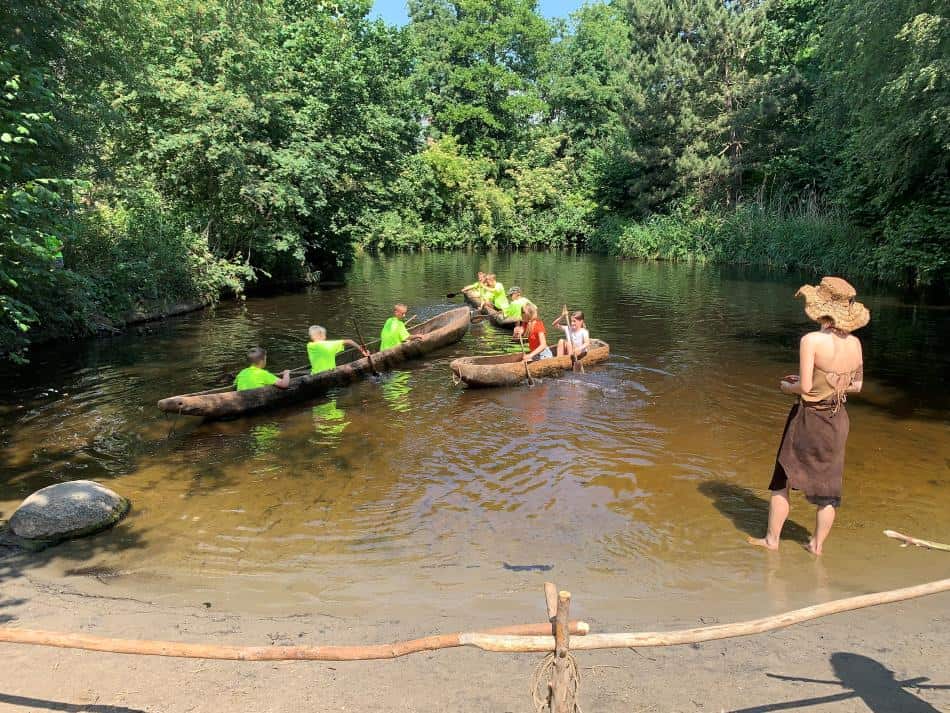 Kinderen in een kano van uitgeholde boomstammen in het Archeon in Alphen