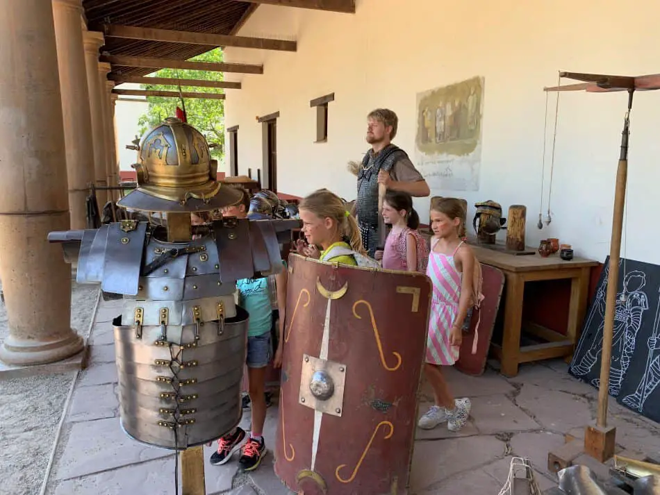 Medewerker van het Archeon, verkleed als Romeinse soldaat, poseert met kinderen voor een foto