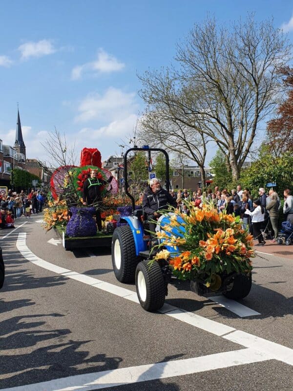 Met bloemen versierde traktor tijdens bloemencorso Bollenstreek